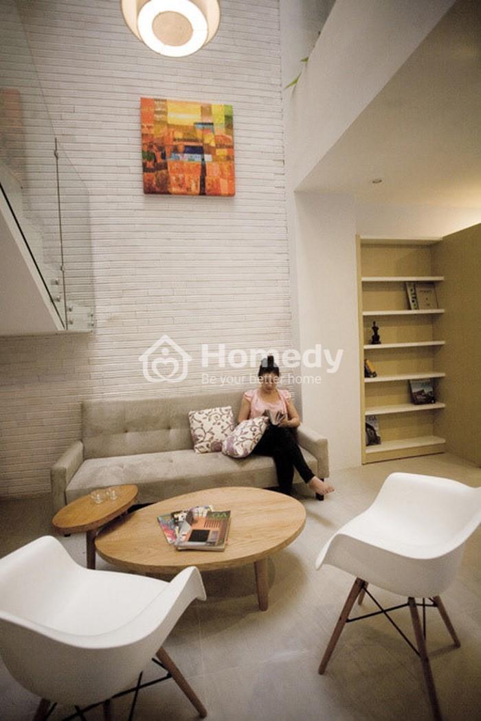 Thiết kế phòng khách nhỏ gọn, ấm cúng với sofa đơn màu ghi xám và bàn trà đôi bằng gỗ.